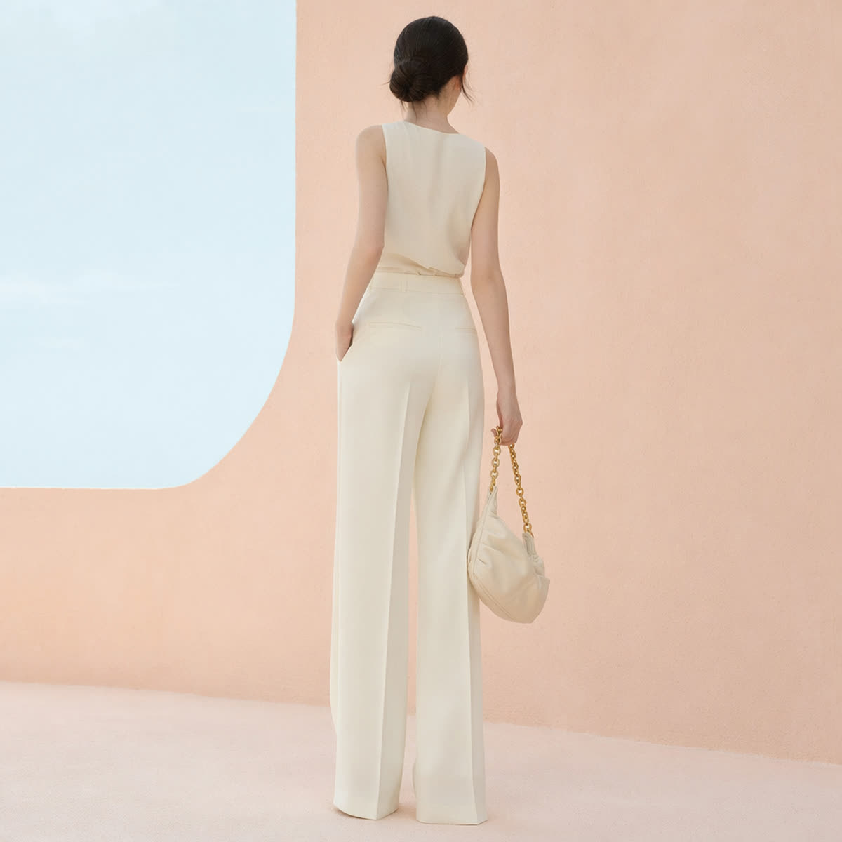 A petite woman in a high-waisted monochrome cream outfit forming one long vertical line